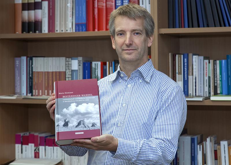 Professor Mario Niemann zeigt stolz sein Buch mit dem Titel „Beständiger Wandel“. 