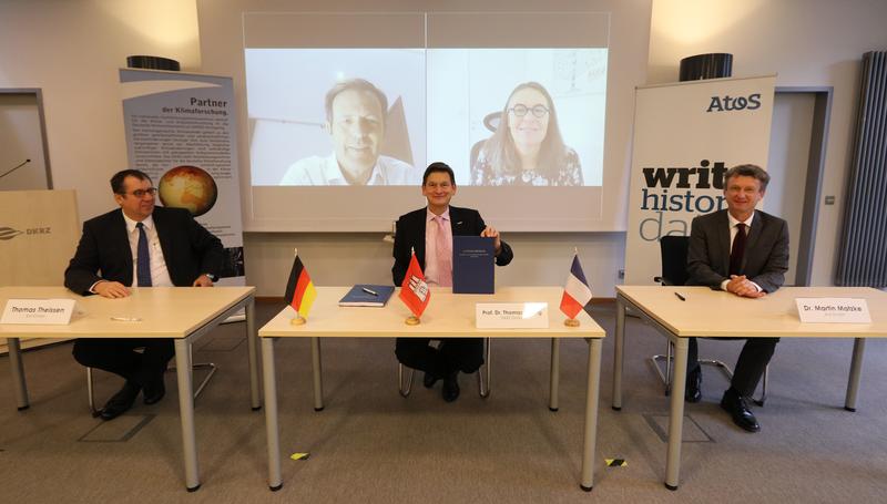 From left to the right: Thomas Theissen, Atos in Germany, Prof. Thomas Ludwig, DKRZ, and Dr. Martin Matzke, Atos Central Europe. Connected via video conference: Philippe Miltin, and Agnès Boudot, both Atos.