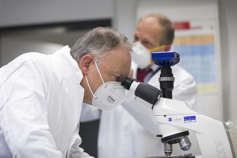 Ministerpräsident Stephan Weil beim Blick durch ein Mikroskop in einem Forschungslabor der DSMZ