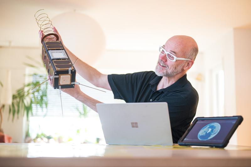 Research in home office: computer scientist Holger Hermanns shows the model of a nano-satellite