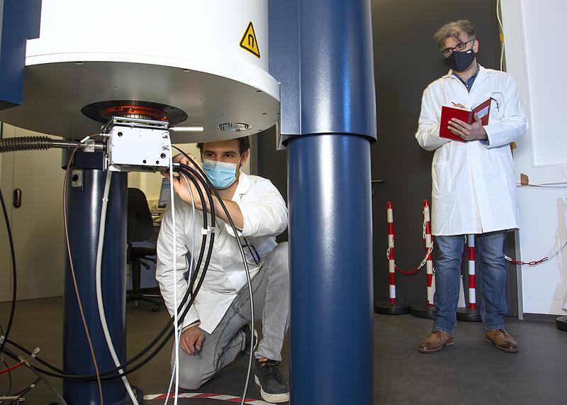 Masterstudent Eduard Mock stimmt den NMR-Probenkopf für das Experiment ab; Postdoktorand Dr. Siavash Saeidpour notiert dabei die Parameter im Laborjournal. 