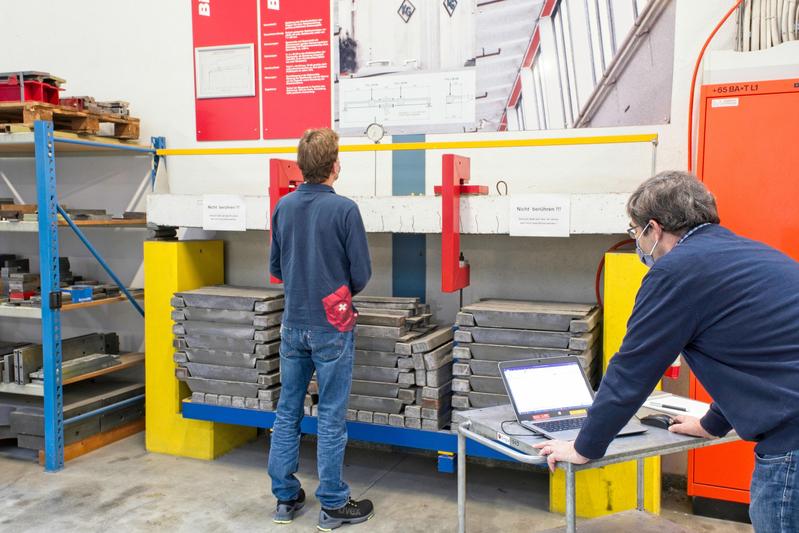 The concrete beam strengthened with a steel plate - "glued" - carries a load of just over six tonnes since 24 March 1970. Empa engineers Christoph Czaderski (right) and Robert Widmann measure the concrete beam 50 years after the start of the experiment.