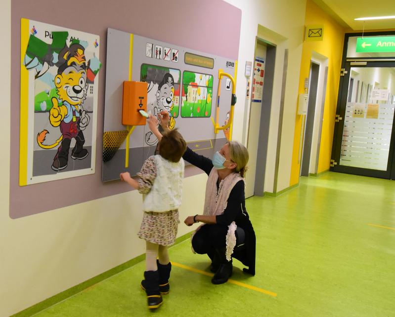 Dr. Katja Albertowski, Leiterin der Autismus-Ambulanz, zeigt Mathilda den originalen Fahrkartenentwerter, den das DVB-Team auf  der Spieltafel montiert hat.