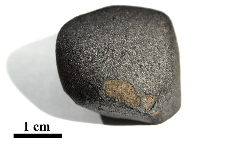 Flensburg-Meteorit mit schwarzer Schmelzkruste: Teile der Schmelzkruste gingen beim Flug durch die Atmosphäre verloren. Das 24,5 Gramm schwere, kleine Bruchstück ist etwa 4,5 Milliarden Jahre alt.