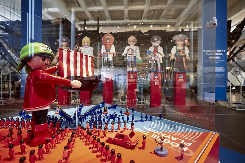 Die Ausstellung "KOGGE trifft PLAYMOBIL – Die Geschichte eines Schiffes neu erzählt" aus der Sammlung von Oliver Schaffer. Im Hintergrund die Kogge.