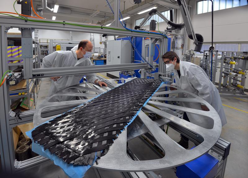 Jakob Schmidt (l.) und Marc Fleischmann, Wissenschaftliche Mitarbeiter an der Professur Textile Technologien der TU Chemnitz, überprüfen auf dem Drehtisch einer Spezialanlage die Qualität der Preform eines Splitboards.