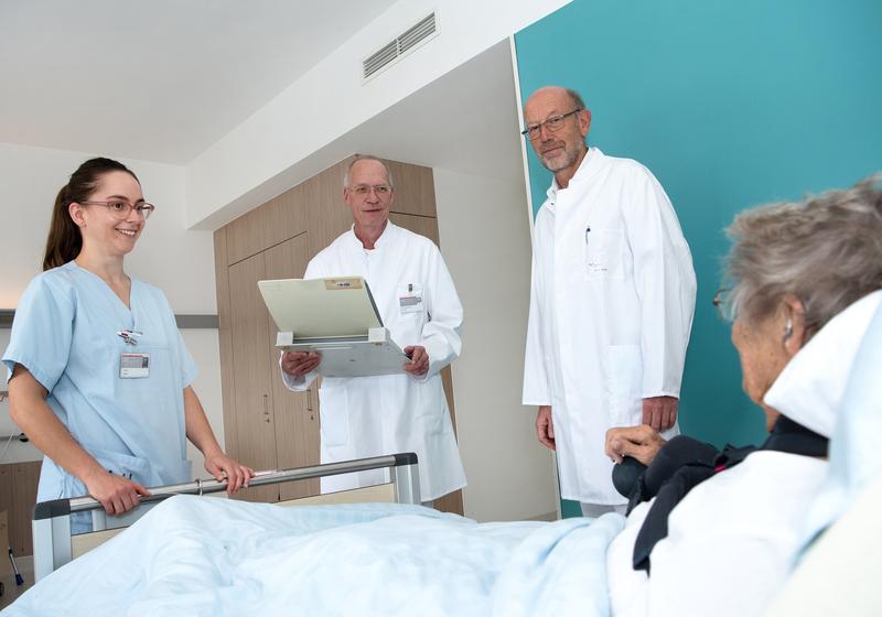 Krankenpflegerin Janina Seeger, Dr. Manfred Gogol und Dr. Lambert Herold (von links) bei der Visite am Bett einer älteren Patientin.