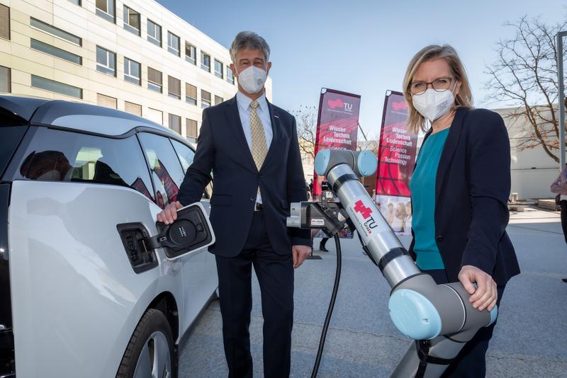 TU Graz Rector Harald Kainz and Federal Minister for Leonore Gewessler test a prototype of an automatic e-charging robot developed at TU Graz.