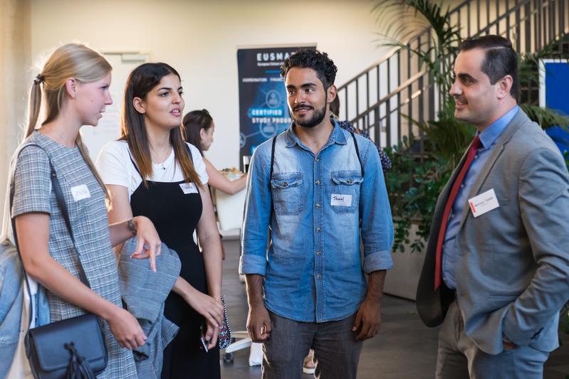 Anna Vikhareva (links) und Daniel Munoz (3.v.l) im Gespräch mit einem Industrievertreter beim Programmpunkt "Meet the expert" (Summer School 2019).