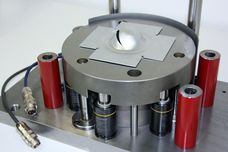 In the testing machine, a hemispherical stamp pushes the component down to a defined depth. 