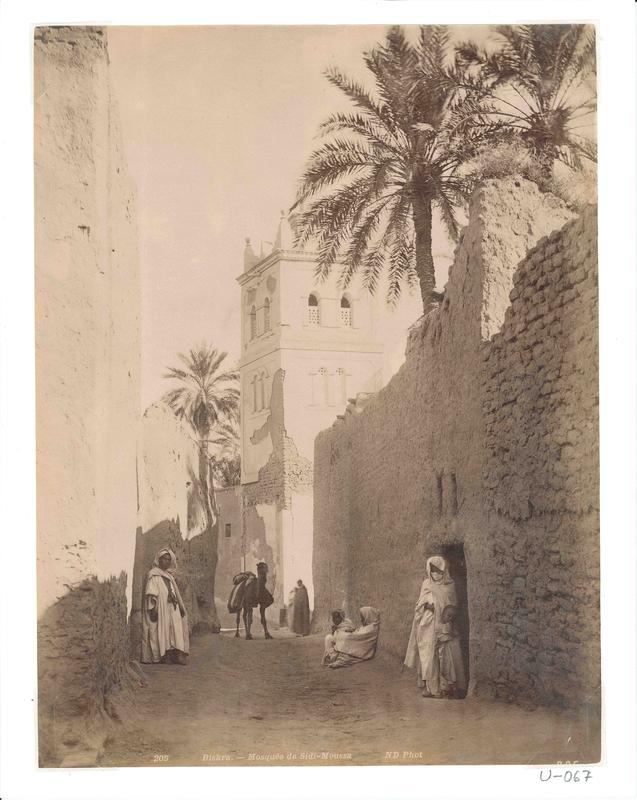 Die Fotografie zeigt die Moschee von Sidi-Moussa in der Stadt Biskra. Die Oasenstadt liegt im östlichen Algerien. Das Bild stammt von dem Fotoatelier Neurdein Frères und wurde im 4. Viertel des 19. Jahrhunderts aufgenommen.