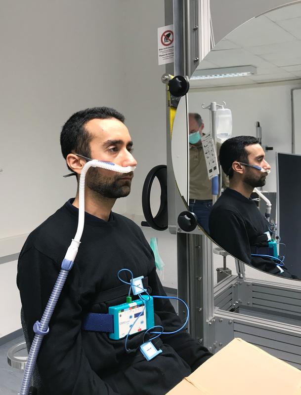 A healthy male test subject outfitted with an NHF therapy device sits in front of the Schlieren mirror.