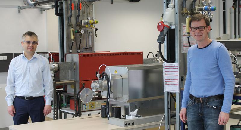 Prof. Dr.-Ing. Stefan Schafföner (li.) und PD Dr. Günter Motz (re.) vor dem Ofen für die Herstellung der Carbonfasern bei 1400 Grad Celsius. 