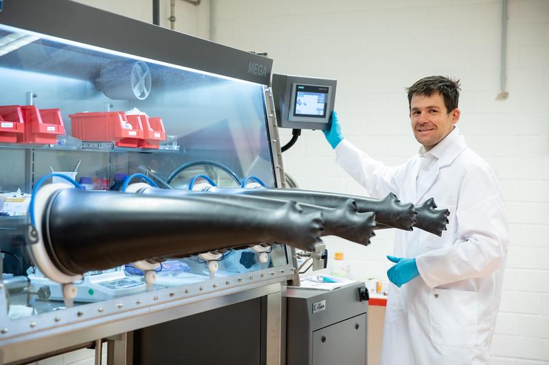 Prof. Oliver Clemens an einer Handschuhbox (Glove-Box), in der luftempfindliche Proben sicher verarbeitet und aufbewahrt werden können.