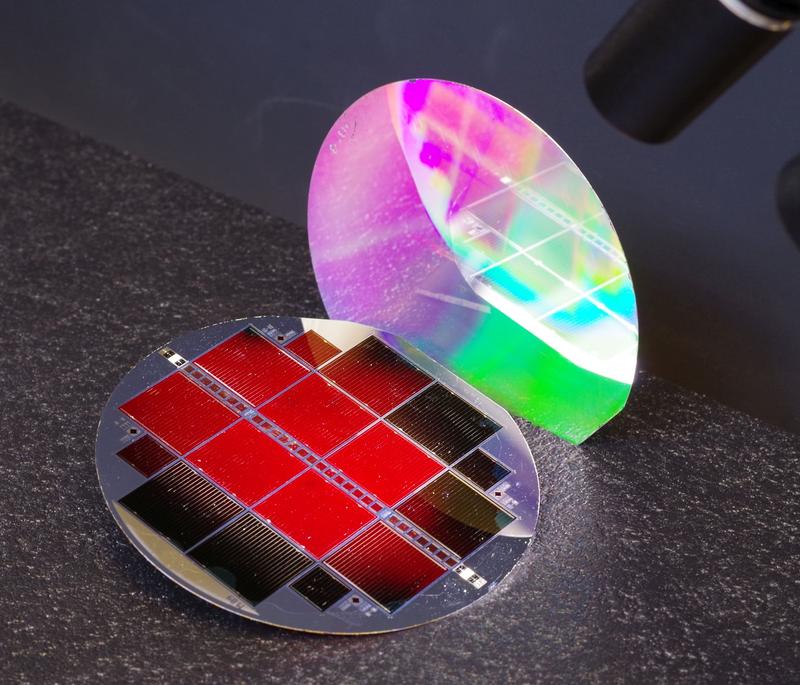 Die neue III-V//Silicium Tandemsolarzelle mit 35,9 % Wirkungsgrad. Die oberste Teilzelle leuchtet rot, ein Zeichen für hervorragende Materialqualität. Die nanostrukturierte Rückseite schimmert in Regenbogenfarben.