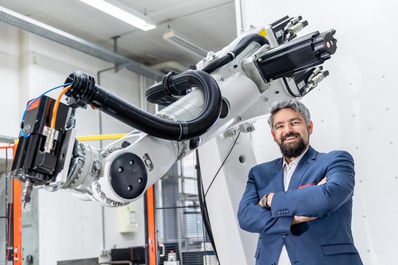 Jun. Prof. Andreas Wortmann vor einem Roboter am Institut für Steuerungstechnik der Werkzeugmaschinen und Fertigungseinrichtungen (ISW) der Universität Stuttgart