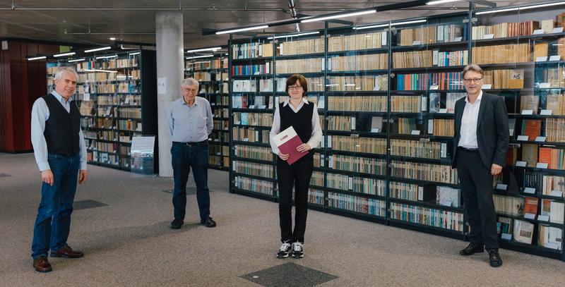 Prof. Dr. Thorsten Unger, Stipendiengeber Prof. em. Dr. Wolfram Neumann, Stipendiatin Bianca Fechtner, Prof. Dr.-Ing. Jens Strackeljan, Rektor, (v.li.n.re.) vor der Buchreihensammlung der Neumann-Stiftung in der Universitätsbibliothek Magdeburg.