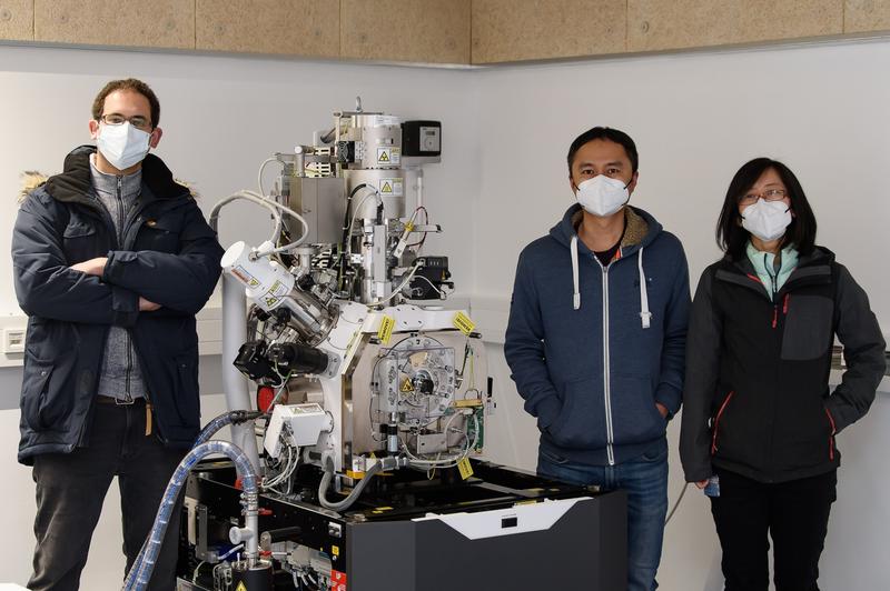 (v.l). Prof. Dr. Rubén Fernández-Busnadiego, Dr. Tat Cheng und Dr. Eri Sakata mit dem angelieferten Kryo-fokussierten-Ionenstrahl-/Rasterelektronenmikroskop. 