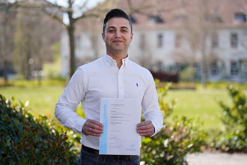  Faruk Güler, geboren und wohnhaft in Wertheim am Main, freut sich, seine Bachelorurkunde in den Händen zu halten