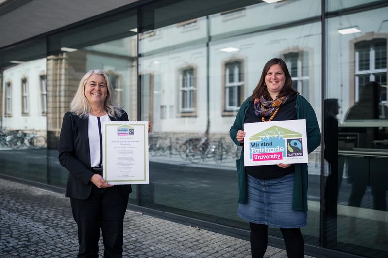 Dagmar Steuer-Flieser, Kanzlerin der Universität Bamberg, und Carolin Brix-Asala, die für die Arbeitsgruppe Fairtrade verantwortlich ist, nehmen die Urkunde entgegen.