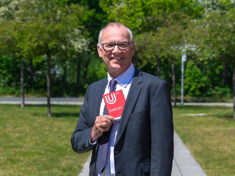 Passt auch ins Jackett: Uni-Rektor und Herausgeber Professor Bernd Scholz-Reiter mit der kleinen und handlichen Jubiläumspublikation, deren Inhalt viel über die Universität Bremen erzählt. 