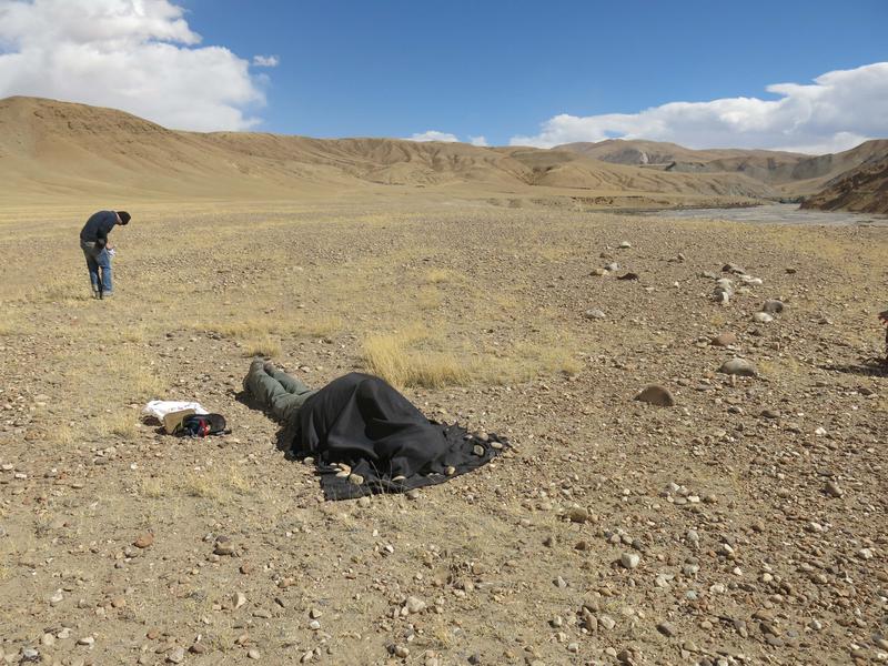 Feldarbeit vor Ort in Tibet: Beprobung der Oberflächenartefakte unter schwarzer lichtundurchlässiger Abdeckplane.  