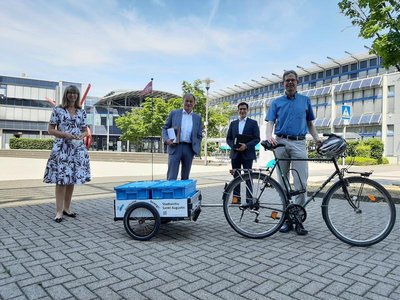 Stadtarchivar Michael Korn (r.) mit Archivgut aus der Hochschule Bonn-Rhein-Sieg. Kanzlerin Angela Fischer, Präsident Hartmut Ihne und Sankt Augustins Bürgermeister Max Leitterstorf (von links) haben zuvor den Kooperationsvertrag unterschrieben.