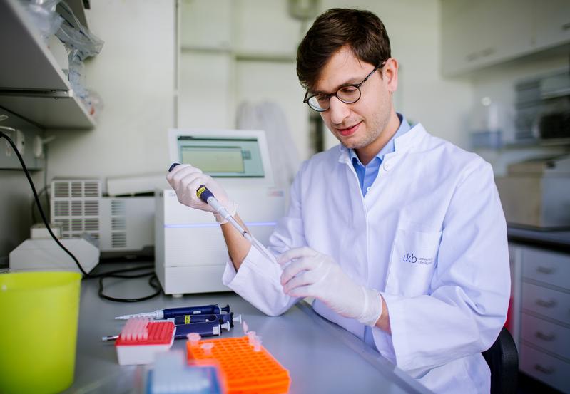 Prof. Dr. Jonathan Schmid-Burgk, aufgenommen beim Pipettieren in einem Labor auf dem Campus des Universitätsklinikum Bonn.