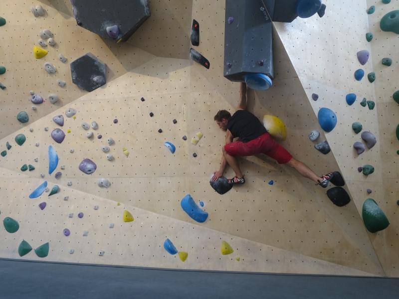 Tim Völzer  in der Rostocker Boulderhalle „45 Grad“.  Die Route, die der 27-Jährige dort klettert, besteht aus den schwarzen Steinen und geht nach links oben