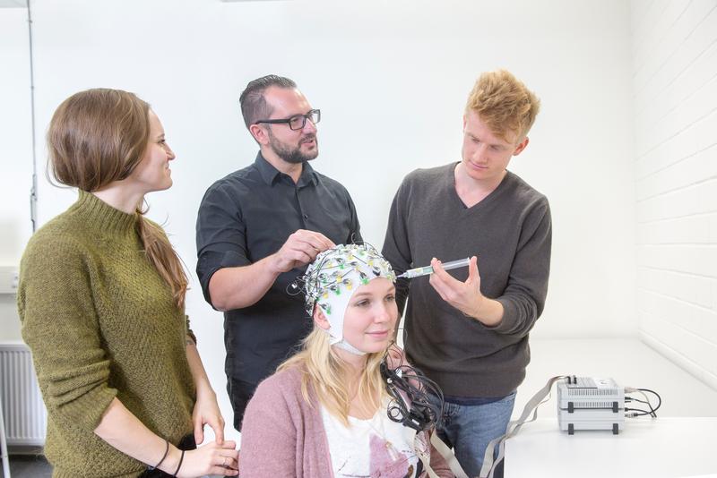 Anhand von EEG-Hauben, hier im Test mit Studierenden und Prof. Dr. Patric Meyer (Mitte), können die Forscher messen, welchen Einfluss der Wechsel zwischen zwei Sprachen auf das Gehirn hat. 