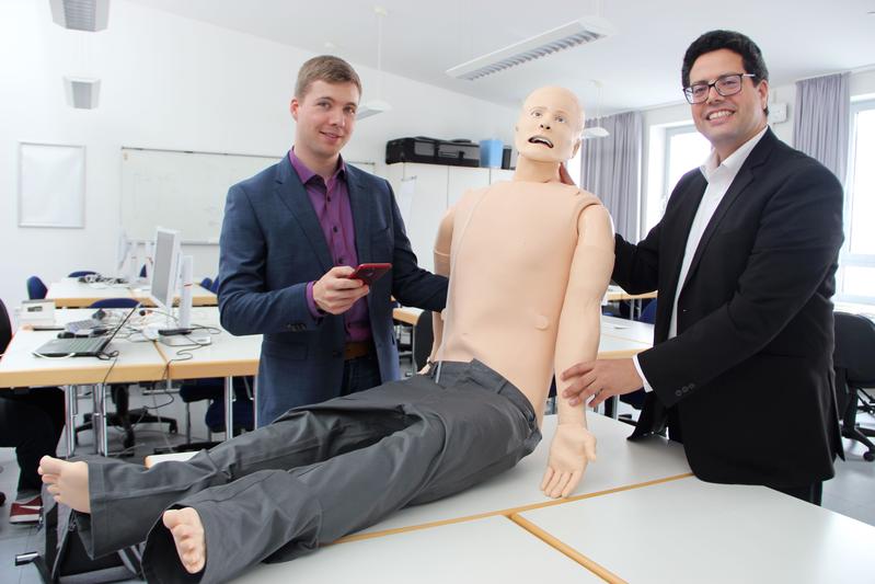 Prof. Dr. Abdelmajid Khelil (rechts) und Tobias Christian Piller (links) arbeiten im Landshuter IoT-Labor u.a. an einer App, die Rettungskräfte bei Unfalleinsätzen unterstützen soll. Getestet wird diese an einer lebensechten technischen Puppe.