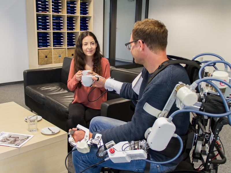 The exoskeleton subsystem enables "Assistive Daily Living" applications, such as grasping and lifting objects. 