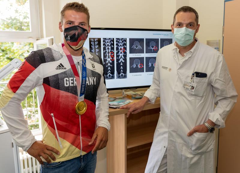 Prof. Alexander Disch, Leiter des Universitäts-Wirbelsäulenzentrums und Koordinator Sportmedizin am OUPC, und Tom Liebscher vor den CT-Aufnahmen der gebrochenen Wirbelfortsätze.