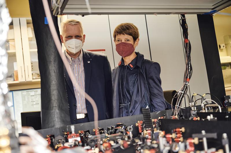 Niedersachsens Wissenschaftsminister Björn Thümler und Angela Ittel, Präsidentin der TU Braunschweig, betrachten gemeinsam das Herz eines Quantencomputerprototypen in Braunschweig.