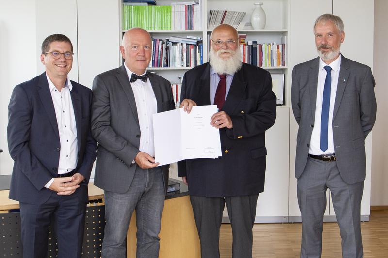 Rektor Prof. Dr. Marcus Baumann überreicht Dr. Roger Uhle (2.v.l.) die Urkunde zur Honorarprofessur.