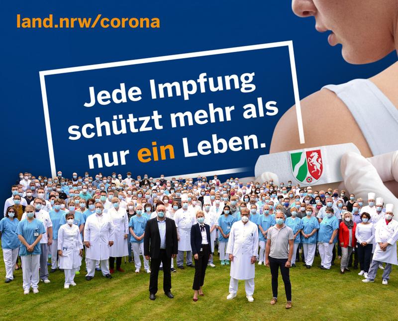 Einigkeit zum Impfschutz: Die Belegschaft des HDZ NRW stellt sich vor dem Motiv der NRW-Landeskampagne auf