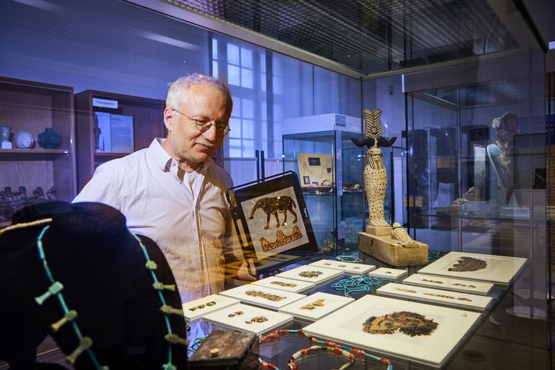 Prof. Dr. Ludwig D. Morenz im Ägyptischen Museum der Universität Bonn. Rechts von ihm ist die Hieroglyphe für die Nilinsel Elephantine zu sehen: oben ein Elefant und unten symbolisch ein Gebirge. 
