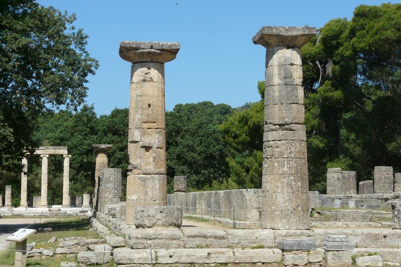 Blick in das Heiligtum von Olympia. Rechts der um 600 v. Chr. errichtete Tempel der Göttin Hera, im Hintergrund links das von Philipp II. von Makedonien gestiftete Philippeion.
