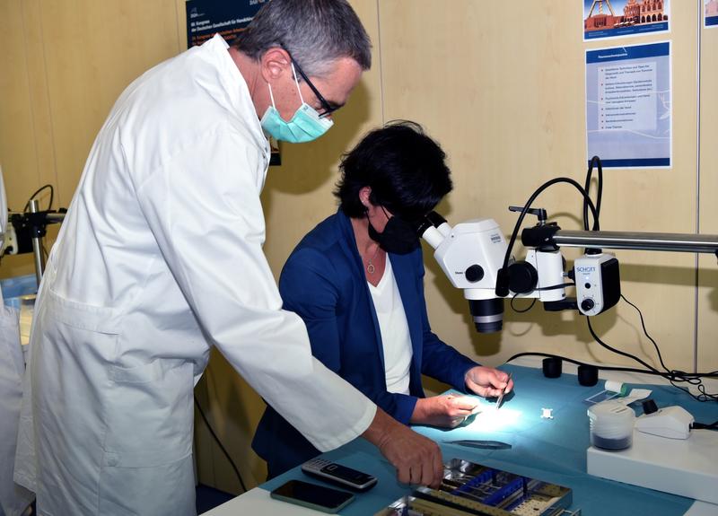 Prof. Dr. Marcus Lehnhardt erläutert Geschäftsführerin Dr. Tina Groll im Trainingszentrum Nahttechniken unter dem OP-Mikroskop