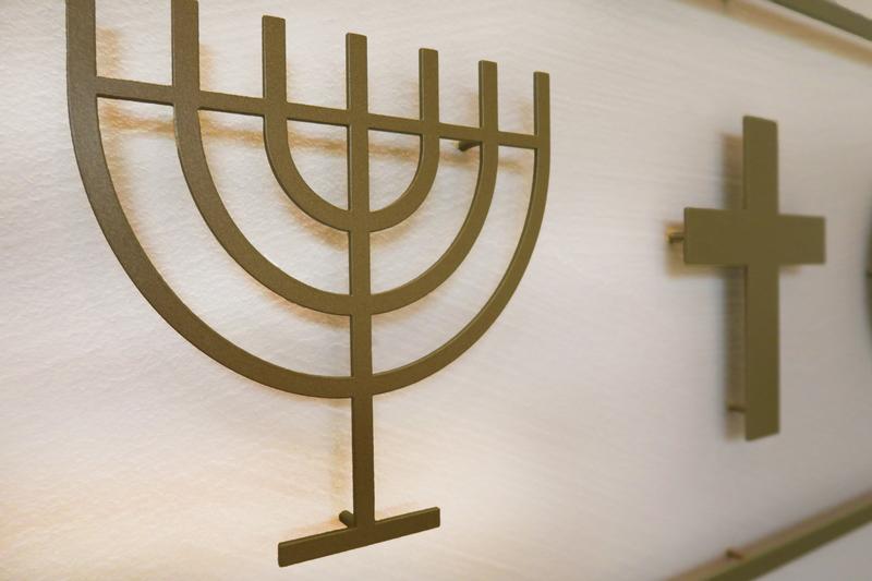 Menorah und Kreuz – Symbole des Judentums und des Christentums; Installation neben anderen religiösen Emblemen im «Raum der Stille» an der Universität Luzern. 