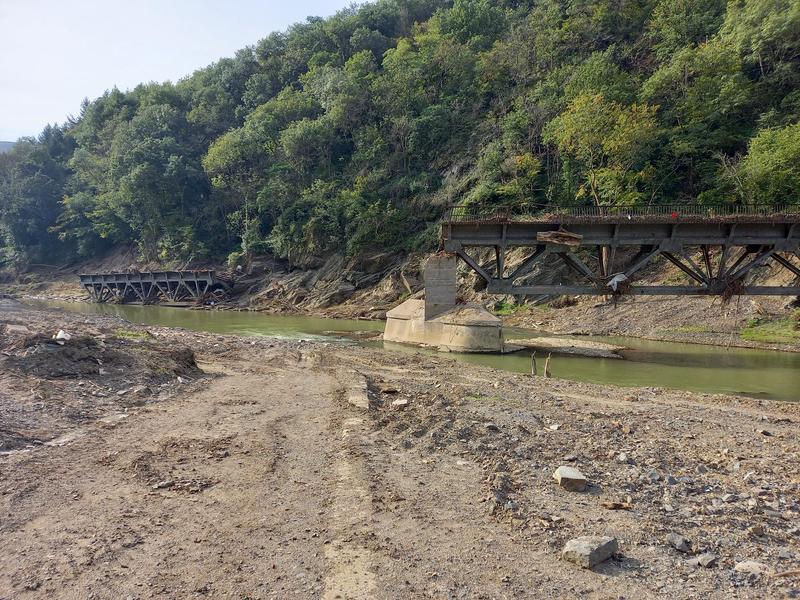 Diese Stahlbrücke wurde trotz ihres Gewichts und ihrer durchlässigen Konstruktion von der Flut durch Totholz und andere Materialien mitgerissen. Da Brücken massive Barrieren für den Durchfluss darstellen, wird ihr Wiederaufbau teilweise diskutiert. 