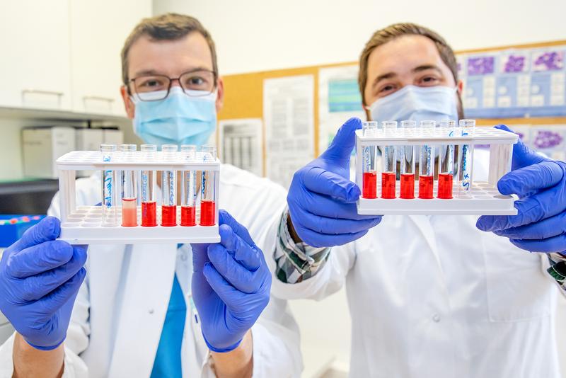   Dr. Christian Schultze-Florey und Dr. Ivan Odak mit Blutserumproben vor einem Durchflusszytometer. 