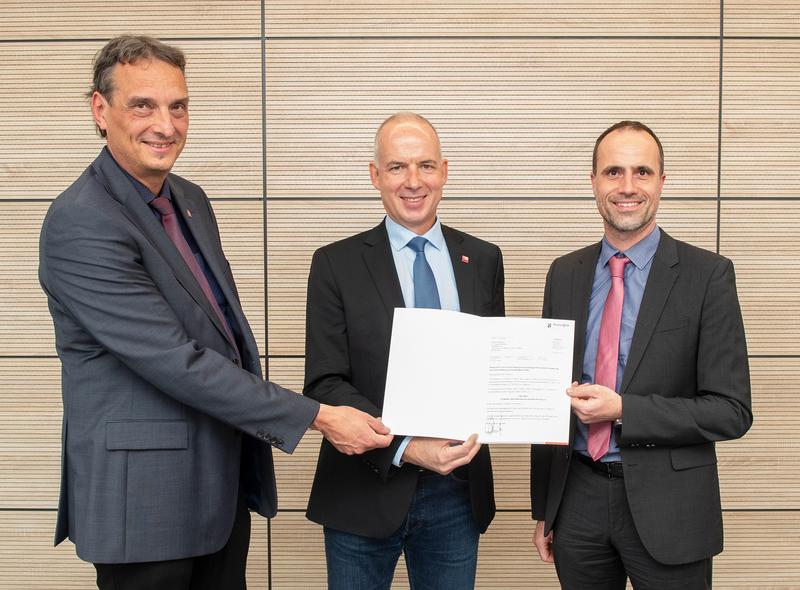 Minister of Science Clemens Hoch (r.) handing over the state grant funding approval for the implementation of the Integrated Core Facility Concept (IRIC) to JGU President Professor Georg Krausch (center) und Vice President Professor Stefan Müller-Stach