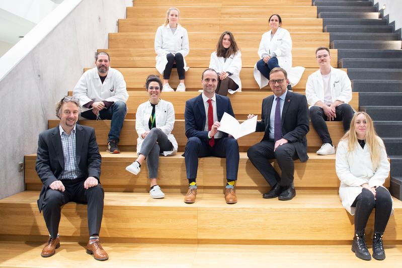 Minister of Science Clemens Hoch (center) presenting the Rhineland-Palatinate state grant for the establishment of the JGU biotechnology guest laboratory to Dean Professor Eckhard Thines before an audience of young international researchers