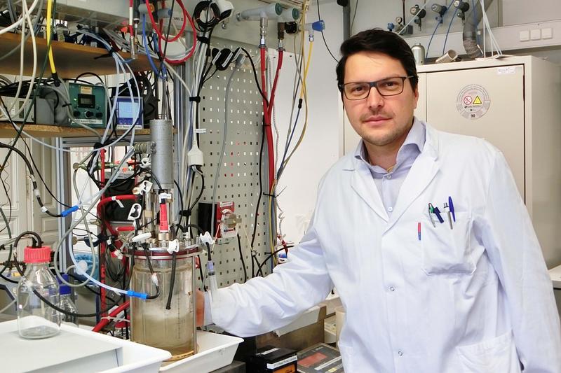 Stefan Pflügl im Labor. Links von ihm ein Bioreaktor. 