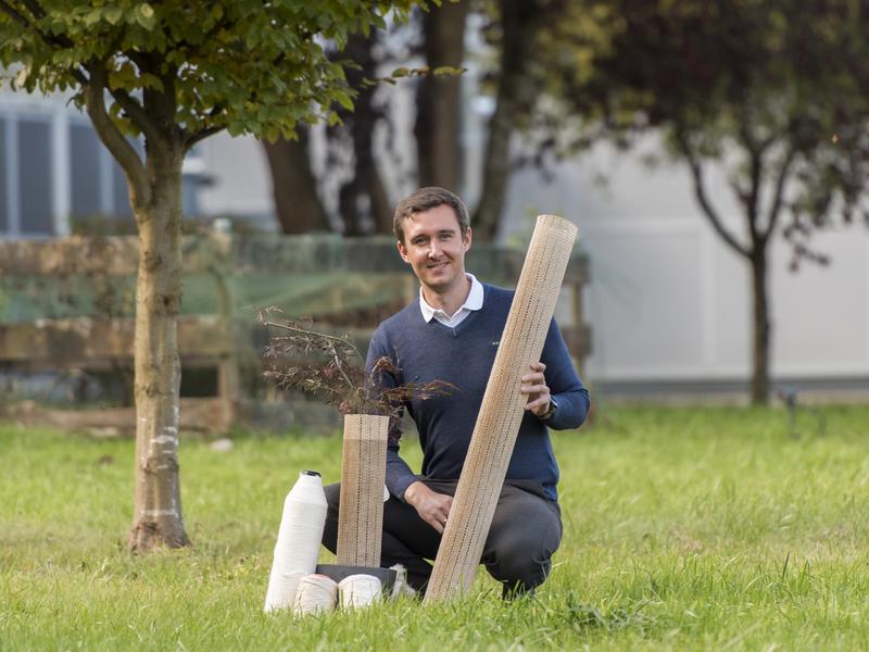 Stephan Baz (Head of Staple Fiber Technologies) with the environmentally friendly tree cover in original size and as a demonstrator on a red maple. In the foreground: hybrid yarn variants made from flax or cotton