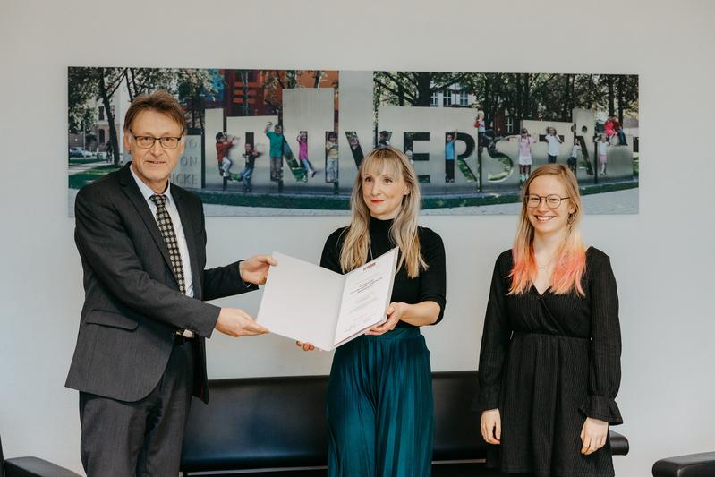 Rektor Prof. Dr.-Ing. Jens Strackeljan (li.) und Jessica Biethahn vom Studierendenrat der Universität (re.) überreichten die Urkunde zur Verleihung des „Lehrpreises der Otto-von-Guericke-Universität Magdeburg 2021“ an Dr.-Ing. Melanie Fachet (Mi.).