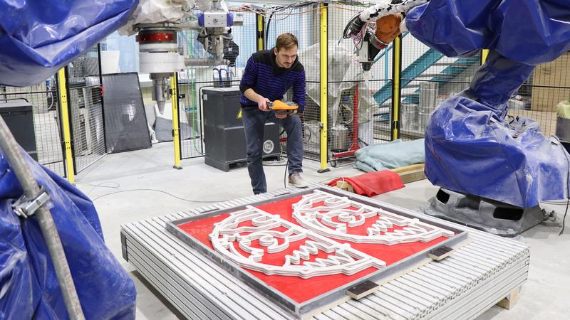 Enrico Rudolph vom Forschungsbereich "Leichtbau im Bauwesen" am Institut für Strukturleichtbau der Technischen Universität Chemnitz untersucht nach der Fertigung der Schwibbögen im Roboter-Komplex die Qualität des Schichtaufbaus des 3D-Betondrucks. 