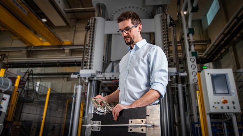 Marcus Hartenstein, Wissenschaftlicher Mitarbeiter an der Professur Strukturleichtbau und Kunststoffverarbeitung der TU Chemnitz, prüft die Dicke eines Organoblechs. Das Element für einen Abfallbehälter wurde im Forschungscluster MERGE gefertigt.