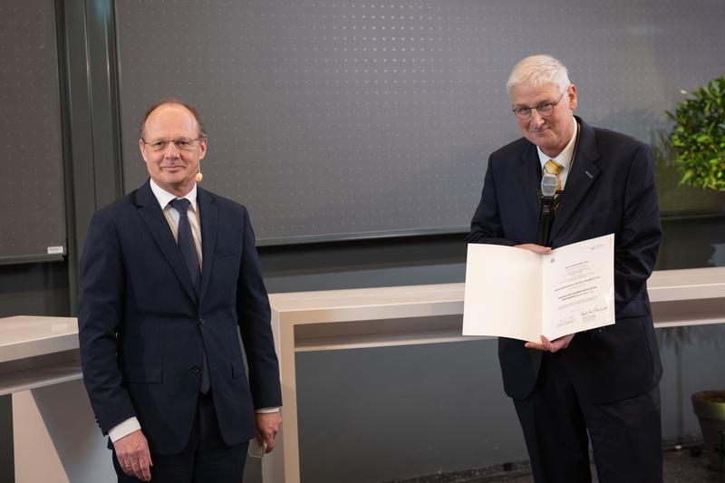 Universitätspräsident Prof. Michael Weber (links) verleiht Prof. Hansjörg Dittus (links) die Ehrendoktorwürde der Fakultät für Naturwissenschaften